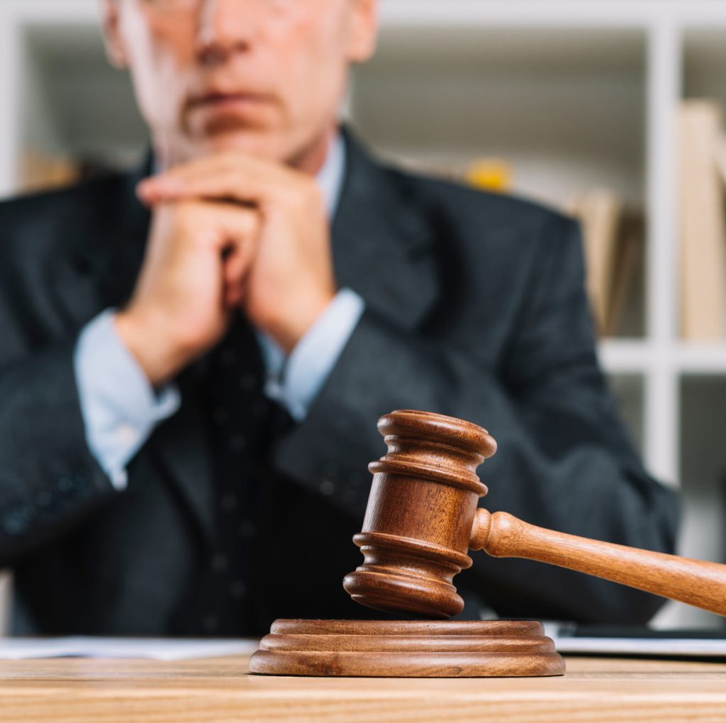 Judge seated behind a gavel with hands clasped