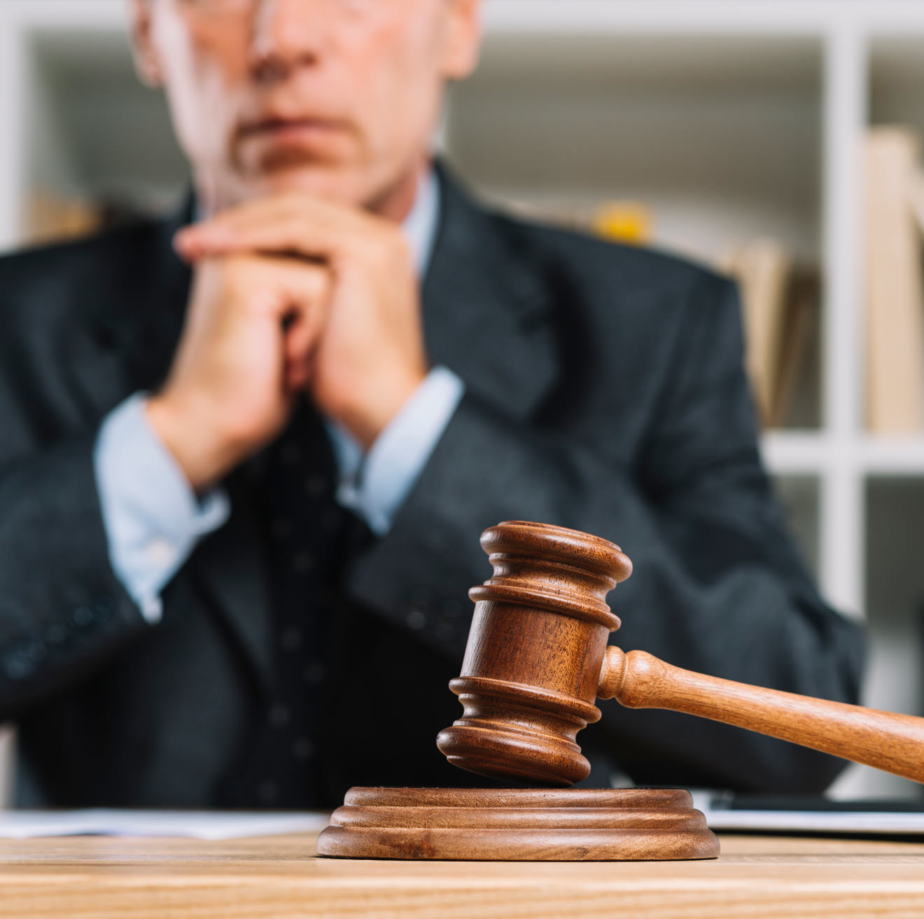 Judge seated behind a gavel with hands clasped