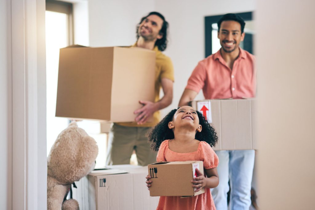 Family carrying moving boxes into a new home