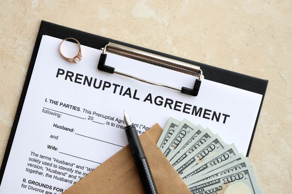 Prenuptial agreement on a clipboard with a pen and cash