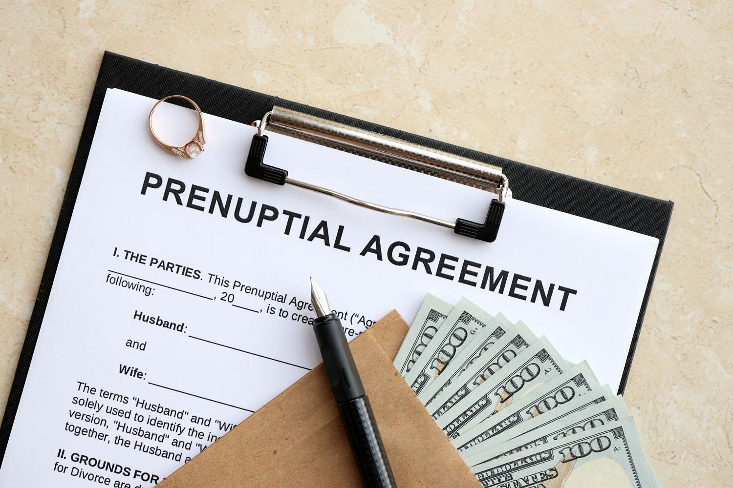 Prenuptial agreement on a clipboard with a pen and cash