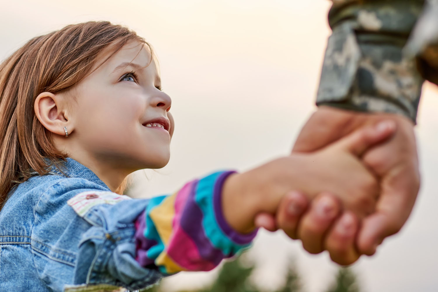 Young girl holding a parent's hand