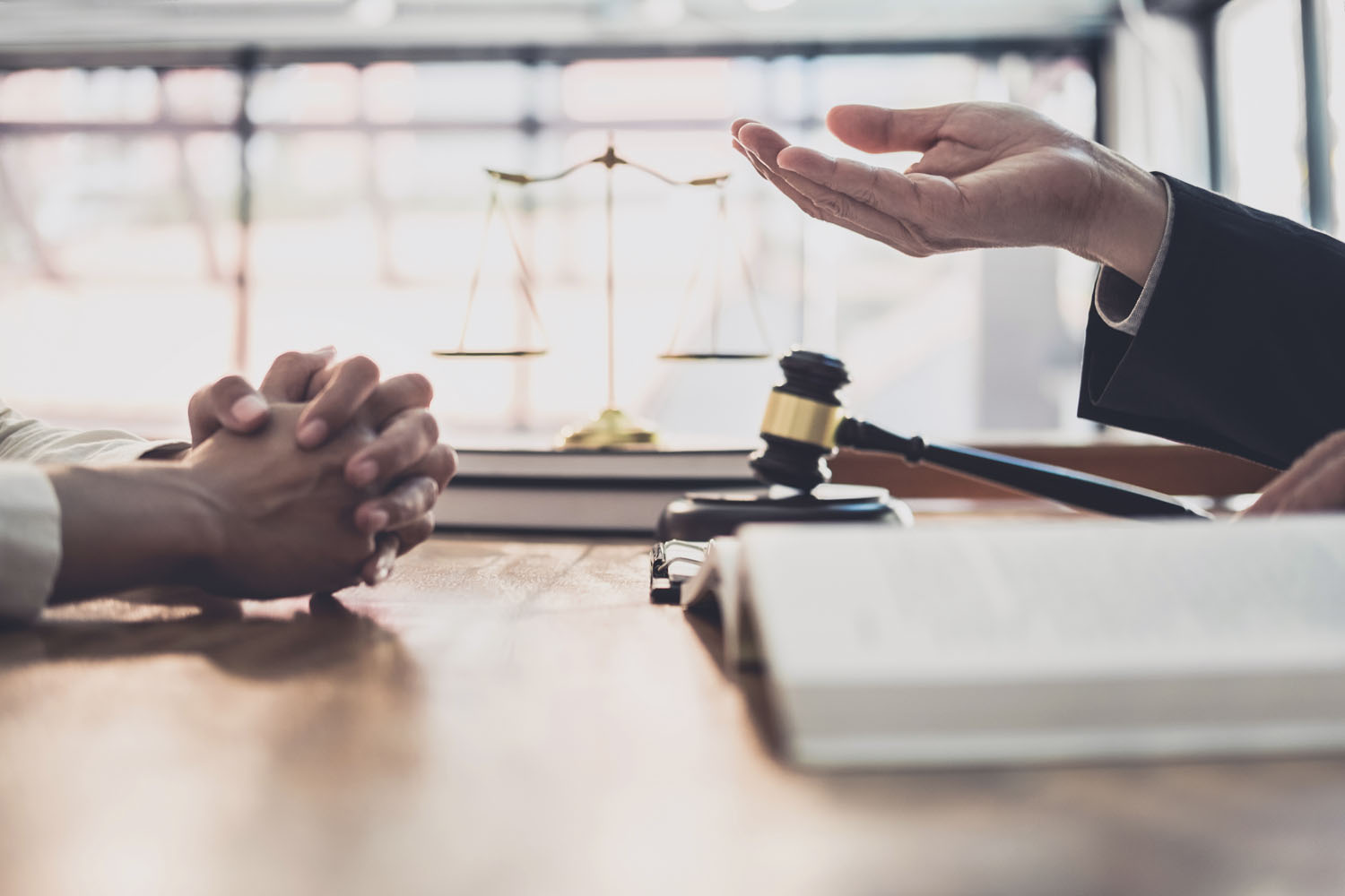 Attorney and client talking across a desk with a gavel and scales of justice