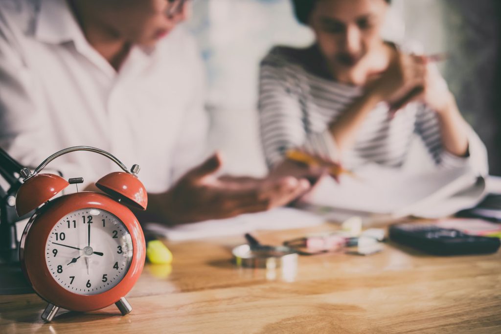 Parent and child reviewing papers beside an alarm clock