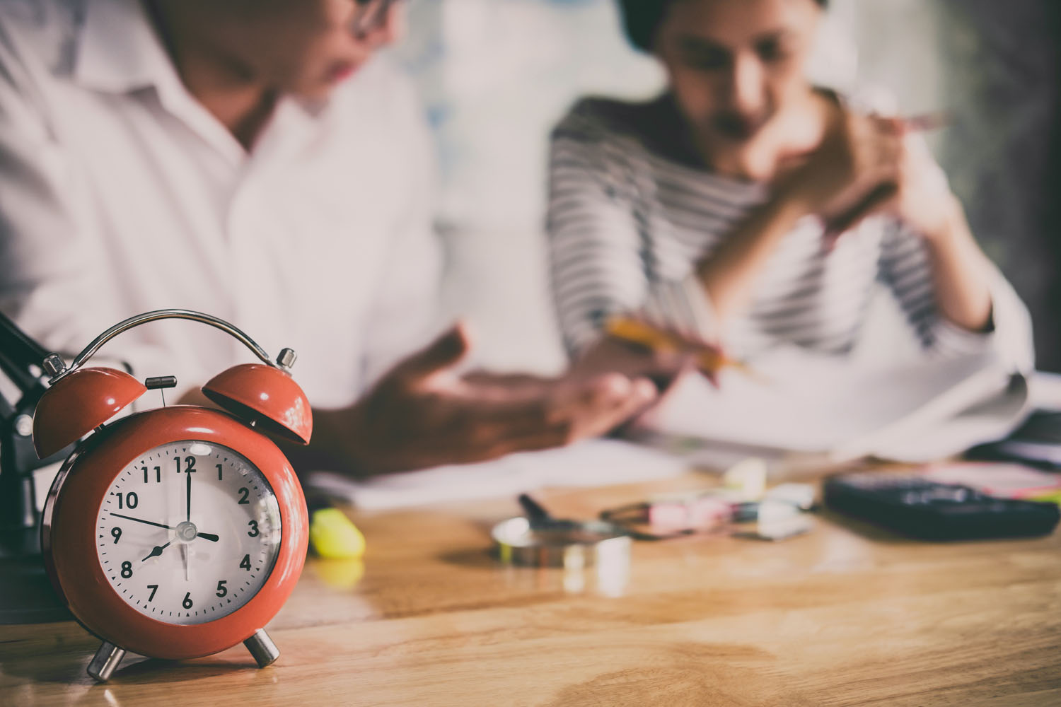 Parent and child reviewing papers beside an alarm clock